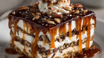 "A layered no-bake turtle lasagna dessert with creamy chocolate pudding, caramel drizzle, whipped topping, and crunchy pecans."