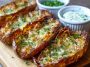 Crispy roasted potato skins topped with garlic, fresh herbs, and melted cheese, served golden brown on a platter.
