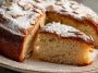 “A golden Italian torta della nonna topped with pine nuts and powdered sugar, sliced to reveal creamy custard filling.”