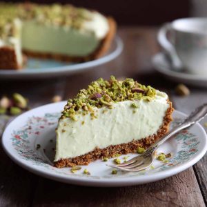 Slice of pistachio cream pie topped with whipped cream and crushed pistachios.