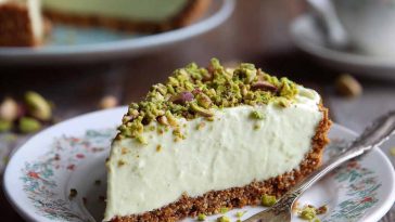 Slice of pistachio cream pie topped with whipped cream and crushed pistachios.