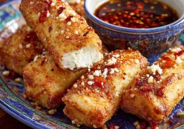Golden oven-fried feta rolls drizzled with spicy chili honey, crispy appetizer with a sweet-heat kick.