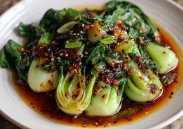 Stir-fried bok choy drizzled with ginger chili sauce and garnished with sesame seeds.