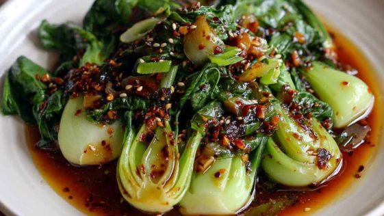 Stir-fried bok choy drizzled with ginger chili sauce and garnished with sesame seeds.