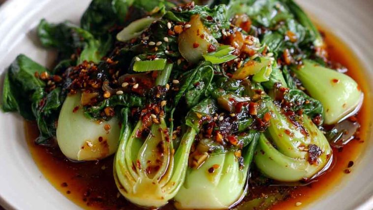 Stir-fried bok choy drizzled with ginger chili sauce and garnished with sesame seeds.