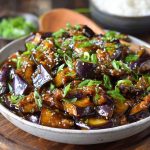 Sautéed Chinese eggplant in garlic sauce, tender eggplant pieces coated in savory, glossy sauce with sesame seeds and scallions.
