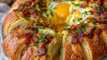 Golden crescent breakfast ring filled with scrambled eggs, cheese, and sausage, baked to perfection and served warm on a platter.