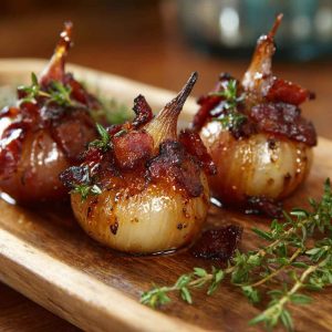 Honey-glazed shallots topped with crispy bacon pieces served in a rustic dish.