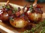 Honey-glazed shallots topped with crispy bacon pieces served in a rustic dish.