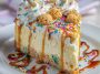 Slice of sugar cookie cheesecake topped with whipped cream and colorful sprinkles.
