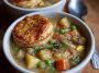 Creamy veggie pot pie soup with carrots, peas, corn, and flaky pastry topping served in a cozy bowl.