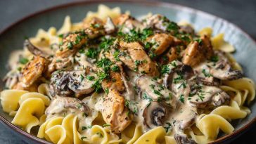 A creamy chicken stroganoff served over egg noodles, garnished with fresh parsley in a rustic bowl.