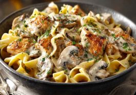 Creamy chicken stroganoff served over egg noodles, garnished with fresh parsley and mushrooms in a rich sauce.