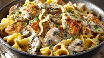 Creamy chicken stroganoff served over egg noodles, garnished with fresh parsley and mushrooms in a rich sauce.
