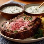 “A creamy bowl of Ina Garten’s horseradish sauce served alongside slices of prime rib roast.”
