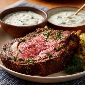 “A creamy bowl of Ina Garten’s horseradish sauce served alongside slices of prime rib roast.”
