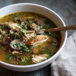 Cozy bowl of rotisserie chicken and mushroom soup, hearty fall comfort food with fresh herbs.