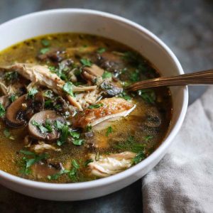 Cozy bowl of rotisserie chicken and mushroom soup, hearty fall comfort food with fresh herbs.