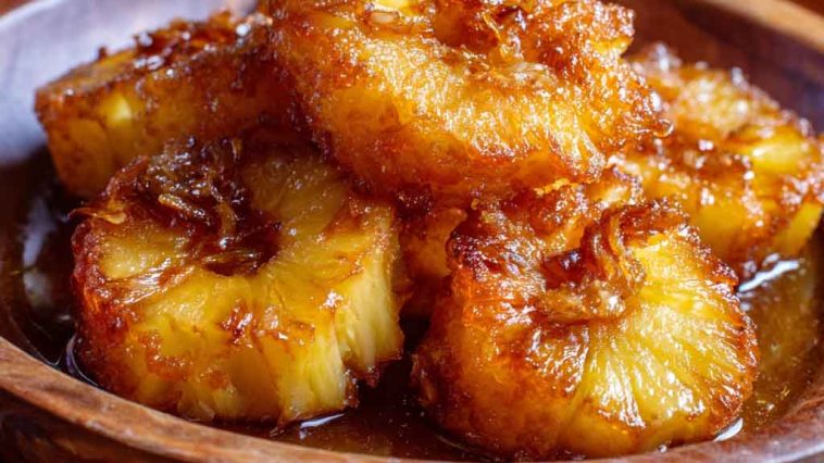 Golden rum-soaked fried pineapple rings caramelized to perfection, topped with a drizzle of syrup and mint garnish.