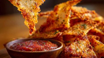 Crispy homemade pizza chips topped with melted cheese, herbs, and pepperoni slices, served as a crunchy snack.