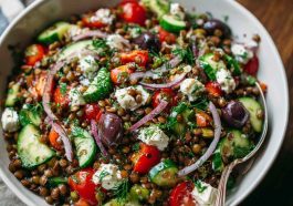 Mediterranean lentil salad with tomatoes, cucumbers, red onion, parsley, and lemon dressing served in a bowl.