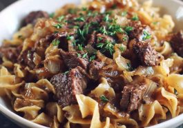 French onion beef and noodles with tender beef strips, caramelized onions, and egg noodles coated in a savory, creamy sauce served in a skillet.
