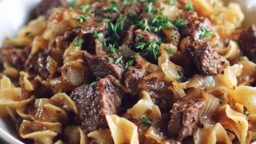 French onion beef and noodles with tender beef strips, caramelized onions, and egg noodles coated in a savory, creamy sauce served in a skillet.