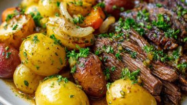 A hearty slow cooker dish with tender garlic butter beef and golden potatoes, garnished with fresh herbs.