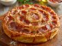 “A golden-brown jumbo pepperoni-stuffed pizza spiral sliced into rounds, oozing with melted cheese and served on a platter.”