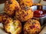 "Golden spicy bacon cheese balls served on a platter, crispy outside with gooey melted cheese inside."