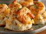 “Golden biscuit melts topped with creamy shrimp and crab filling, garnished with herbs and melted cheese.”