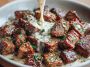 Garlic butter steak bites served in a skillet, coated in creamy Parmesan sauce with fresh herbs, ready to enjoy as a savory dinner or appetizer.