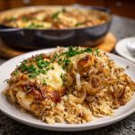 One-pot French onion chicken rice dinner cooked in a skillet, featuring tender chicken, caramelized onions, melted cheese, and fluffy rice garnished with fresh herbs.