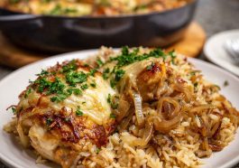 One-pot French onion chicken rice dinner cooked in a skillet, featuring tender chicken, caramelized onions, melted cheese, and fluffy rice garnished with fresh herbs.