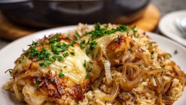 One-pot French onion chicken rice dinner cooked in a skillet, featuring tender chicken, caramelized onions, melted cheese, and fluffy rice garnished with fresh herbs.