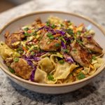 Potsticker noodle bowl with pork, noodles, and fresh cabbage slaw served in a bowl.