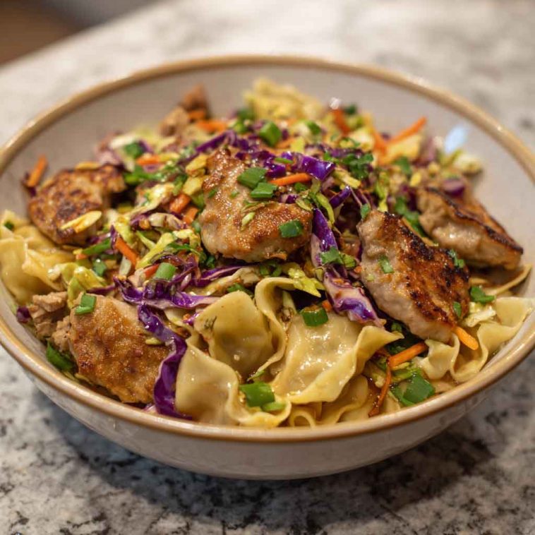 Potsticker noodle bowl with pork, noodles, and fresh cabbage slaw served in a bowl.