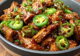 Irresistible sweet jalapeño pork served in a skillet with tender pork pieces glazed in a sweet and spicy jalapeño sauce, garnished with fresh cilantro and lime wedges.