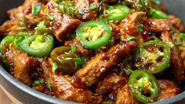 Irresistible sweet jalapeño pork served in a skillet with tender pork pieces glazed in a sweet and spicy jalapeño sauce, garnished with fresh cilantro and lime wedges.