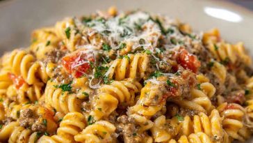 Creamy Rotel pasta with ground beef served in a skillet, featuring tender pasta coated in a cheesy Rotel tomato sauce with seasoned ground beef, garnished with fresh parsley.