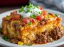 Easy cowboy casserole baked in a skillet with ground beef, beans, corn, cheese, and crispy tater tots, served hot and golden brown.