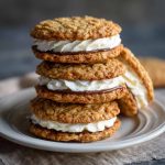 Homemade oatmeal cream pies with soft, chewy oatmeal cookies sandwiched together with a fluffy vanilla cream filling, stacked on a plate for serving.