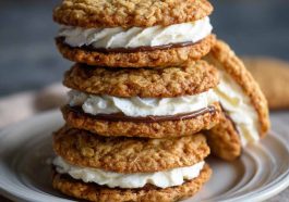 Homemade oatmeal cream pies with soft, chewy oatmeal cookies sandwiched together with a fluffy vanilla cream filling, stacked on a plate for serving.