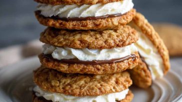 Homemade oatmeal cream pies with soft, chewy oatmeal cookies sandwiched together with a fluffy vanilla cream filling, stacked on a plate for serving.