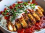 Cottage cheese chicken parm bowl with crispy breaded chicken, marinara sauce, melted mozzarella, and creamy cottage cheese served over pasta or rice, garnished with fresh basil.