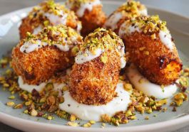 Golden sweet potato croquettes served on a platter with creamy burrata dip, topped with crushed pistachios and fresh herbs, arranged elegantly for a gourmet appetizer.