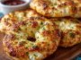 Golden garlic-Parmesan cottage cheese bagels topped with melted cheese and herbs on a wooden board.