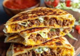 Golden keto crunchwrap cut in half, showing layers of beef, cheese, lettuce, and sour cream.