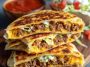 Golden keto crunchwrap cut in half, showing layers of beef, cheese, lettuce, and sour cream.