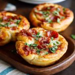 Mini deep dish crescent roll pizzas baked in muffin tins, filled with marinara sauce, melted mozzarella, and pepperoni, served hot and golden brown.